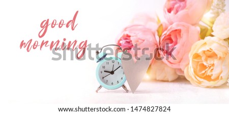 good morning concept. clock alarm and bouquet of pink flowers on light abstract background. Spring summer season. 