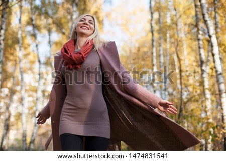 Young woman in autumn forest. Female person in short dress and looking up