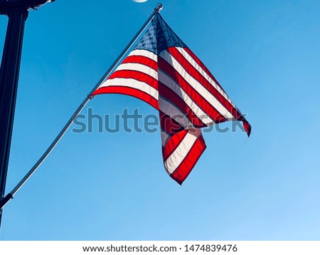 A close up of an American flag blowing on a flagpole