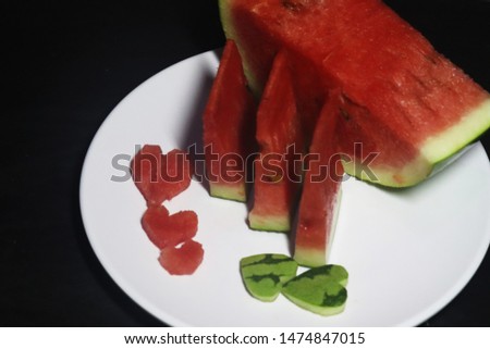 Watermelon pieces on a white plate with a dark background