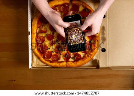 Photographing pizza on smartphone. Delivered pizza in a box, delicious pizza.