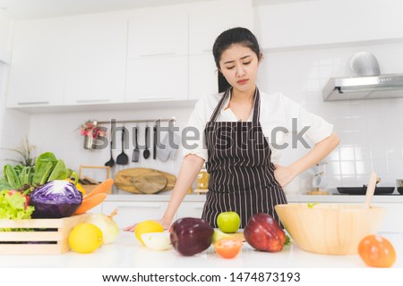 Young woman or housewife is tired of cooking, which consists of a variety of fruits and vegetables for the family. Royalty-Free Stock Photo #1474873193
