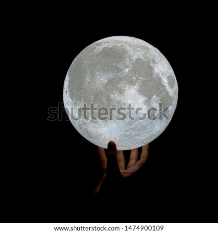 Image of moon held by a hand creating a surreal and conceptual image evoking the imagination
