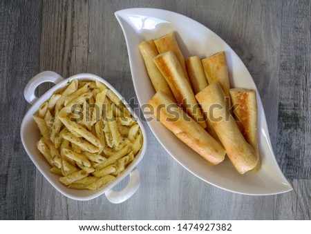 Penne pasta with creamy alfredo sauce and breadsticks.