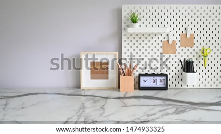 Workspace marble desk with pegboard, photo frame, pencil pot and office supplies.