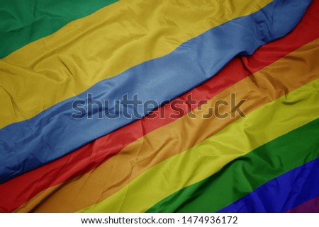 waving colorful gay rainbow flag and national flag of gabon. macro