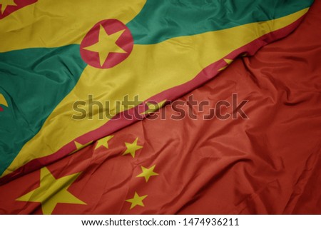waving colorful flag of china and national flag of grenada. macro