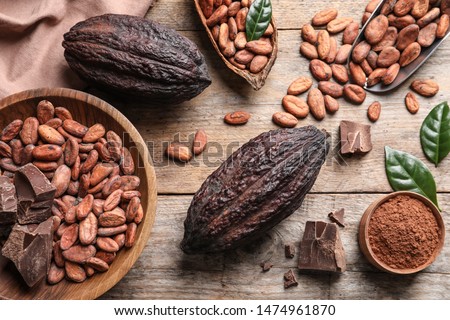 Flat lay composition with cocoa beans, chocolate pieces and pods on wooden table Royalty-Free Stock Photo #1474961870