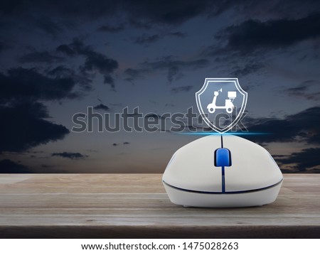 Motorcycle with shield flat icon on wireless computer mouse on wooden table over sunset sky, Business motorbike insurance online concept