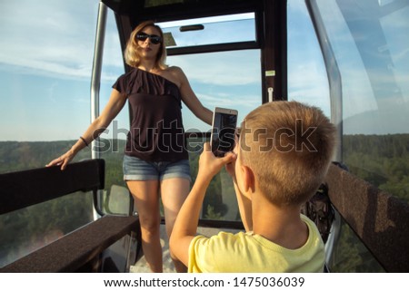A boy takes pictures of his mother in the cab of the funicular