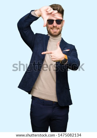 Young handsome elegant man wearing sunglasses smiling making frame with hands and fingers with happy face. Creativity and photography concept.