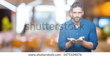 Young handsome man over isolated background Smiling with hands palms together receiving or giving gesture. Hold and protection