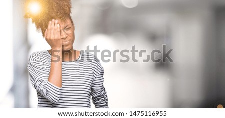 Beautiful young african american woman wearing glasses over isolated background Yawning tired covering half face, eye and mouth with hand. Face hurts in pain.