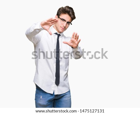 Young business man wearing glasses over isolated background Smiling doing frame using hands palms and fingers, camera perspective
