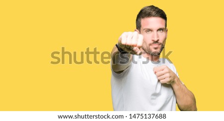 Handsome man wearing casual white t-shirt Punching fist to fight, aggressive and angry attack, threat and violence