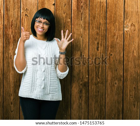 Beautiful young african american woman wearing glasses over isolated background showing and pointing up with fingers number six while smiling confident and happy.