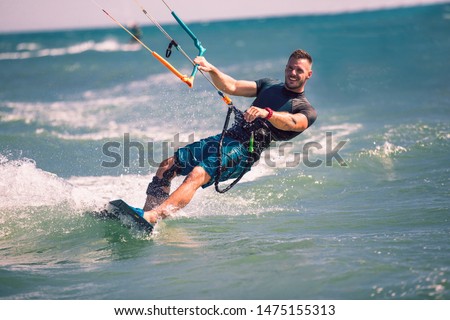 Kitesurfing. Man rides on kite on waves