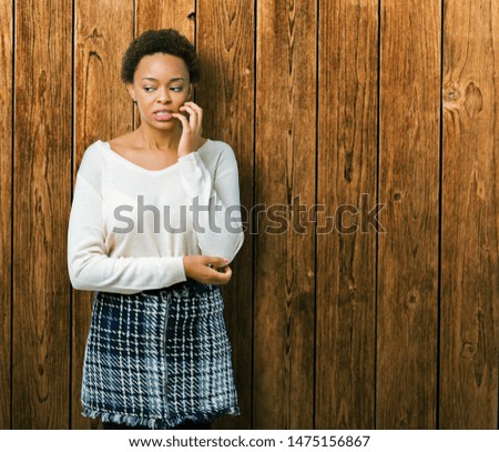 Young african american woman over isolated background looking stressed and nervous with hands on mouth biting nails. Anxiety problem.