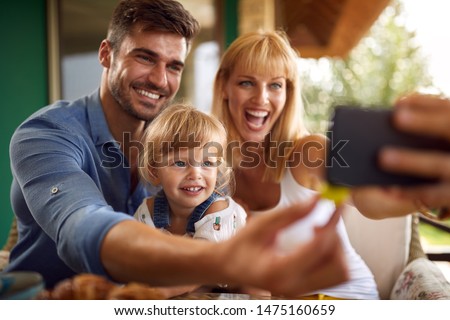 Cheerful parents with cute daughter taking selfie