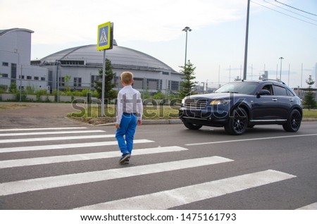 A little boy crosses the street at a pedestrian crossing. The car stopped and misses the child. Child safety on the road.