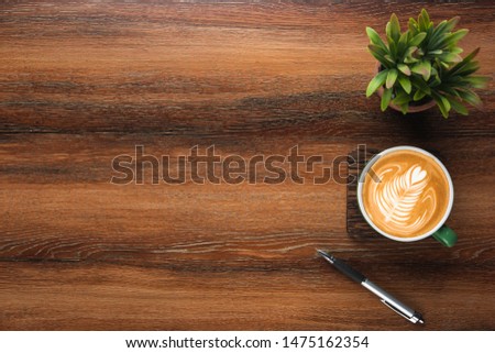Wood office desk table with cup of coffee, pen and plant pot. Top view with copy space, flat, lay.
