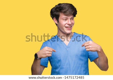 Young doctor wearing medical uniform over isolated background looking confident with smile on face, pointing oneself with fingers proud and happy.