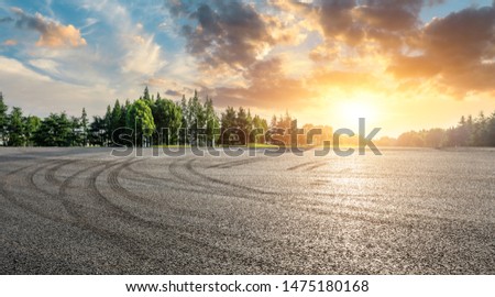 Asphalt race track and green woods nature landscape at sunset