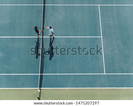 Aerial view of two young man shaking hands on hard court. Tennis players shaking hands over the net after the match. Royalty-Free Stock Photo #1475207297