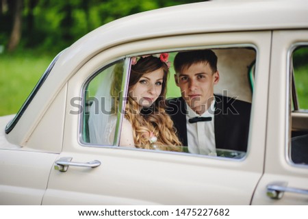 Happy bride and groom, newlywed wedding couple is sitting in a retro car on a country road for honeymoon after the ceremony. Way. The best day and marriage. Just married.