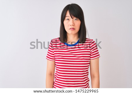 Young beautiful chinese woman wearing red striped t-shirt over isolated white background Relaxed with serious expression on face. Simple and natural looking at the camera.