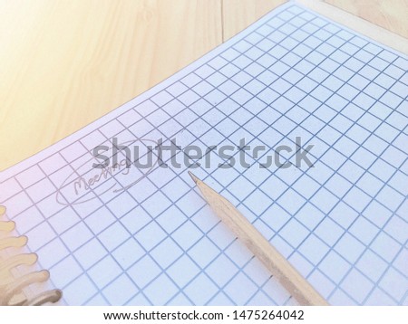 White paper with small dividing lines equal to the whole sheet, look like paper for sketching pictures. Written meeting word with a pencil not dark, with artificial light and process to pastel tone