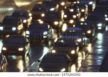 Defocused image of hard night for drivers. Big traffic in the city. In the summer urban highway filled cars. To be late. Long exposure. For greeting card design, postcard template, guide, poster.