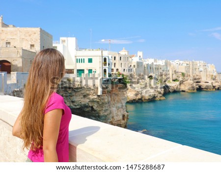 Back view of beautiful young woman in Polignano a mare town on Mediterranean Sea, Italy.