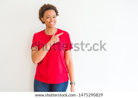 Young beautiful african american woman over white background cheerful with a smile of face pointing with hand and finger up to the side with happy and natural expression on face