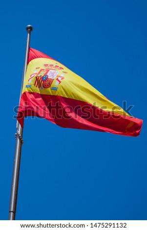 Spanish flag close up waving over a clear blue sky. National flag of Spain on a pole.