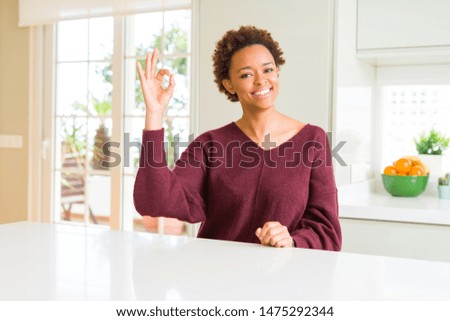 Young beautiful african american woman at home smiling positive doing ok sign with hand and fingers. Successful expression.