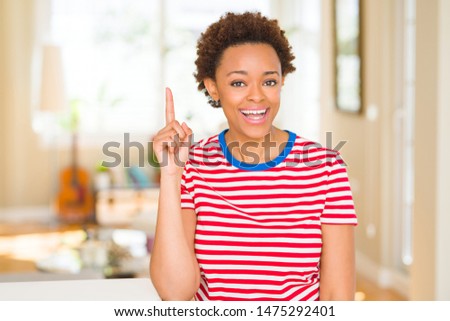 Young beautiful african american woman at home pointing finger up with successful idea. Exited and happy. Number one.