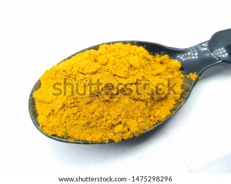 A picture of turmeric powder on black spoon
