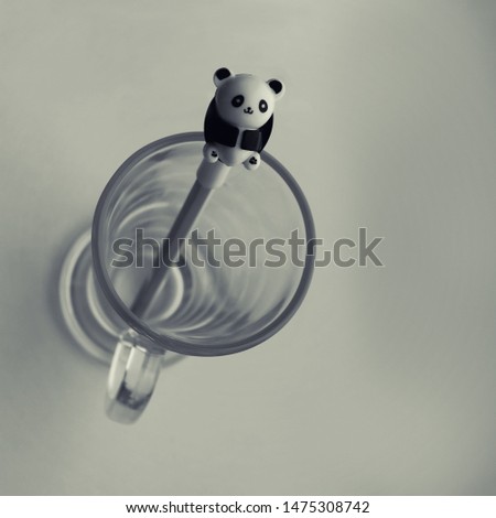 Pencil in a transparent glass. Panda figurine. Top view. High key concept.