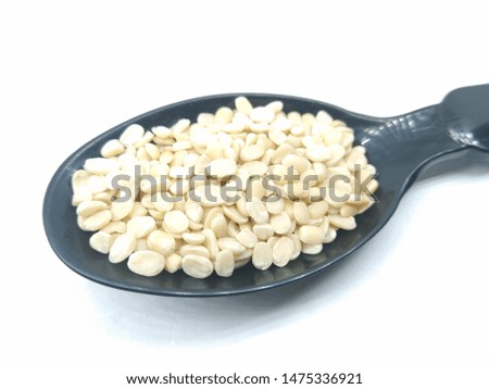 A picture of split black lentil on a black spoon