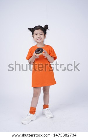 Asian little cute girl eating big donut, isolated on white background