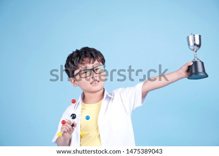 Little Asian boy learning chemical in science with white blouse coat, isolated on blue background