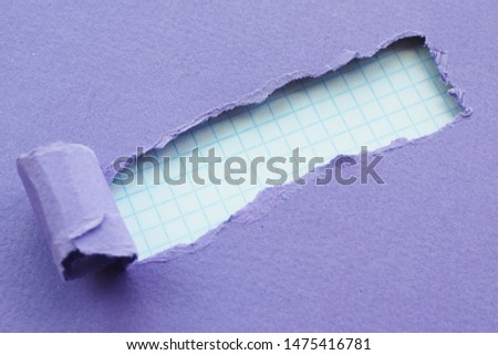 a hole with torn edges of purple paper and checkered paper in the background. Space for text.

