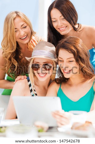 summer holidays, vacation, internet and technology - girls looking at tablet pc in cafe