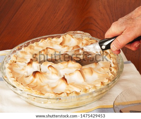 Fresh homemade and delicious lemon meringue pie being served; tasty pie on a tea towel being sliced and served