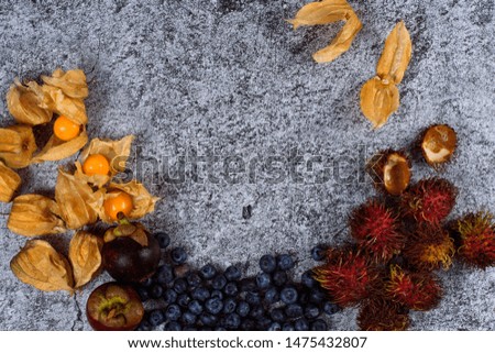 Exotic fruits and berries on newspaper napkins on a concrete background. Horizontal orientation. topView.