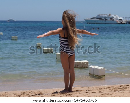 portrait of a girl of 9 years of European appearance with flowing long hair tossing in the wind on a sea sandy beach