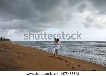 Young couple in love whirling and hugging on tropical ocean beach
