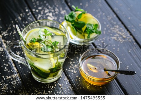 Fresh mint tea with lemon slices and honey on a dark background.