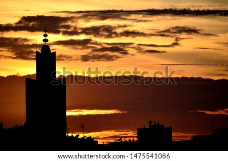 Sunset over the city, a mosque and buildings in silhouette on multicolored sky background.
